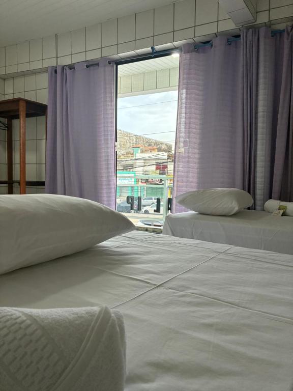 2 letti in una camera con tende viola e finestra di Apartamento Flat em Belém a Belém