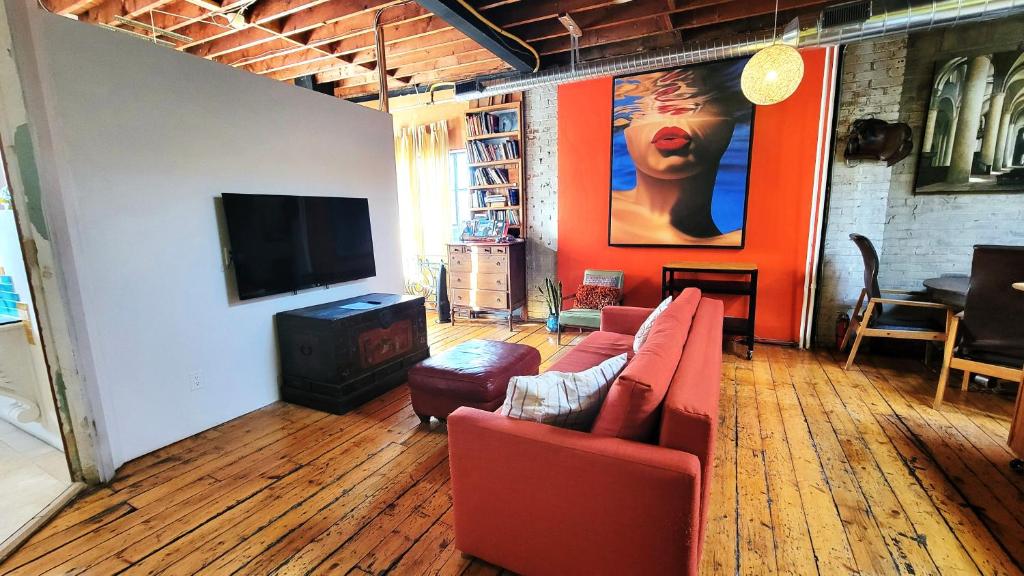 ein Wohnzimmer mit einem roten Sofa und einem Flachbildfernseher in der Unterkunft Unique Above Garage Loft in Toronto