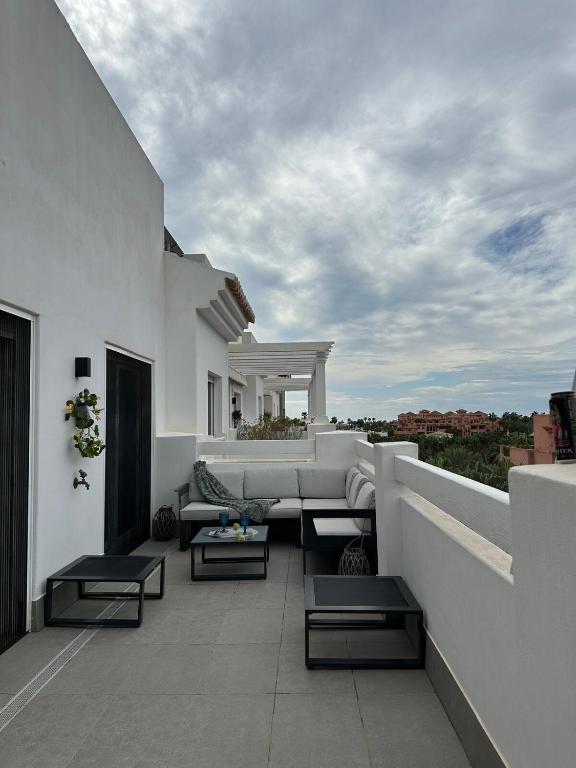 a patio with a couch and tables on a balcony at Dos Mundos in Motril