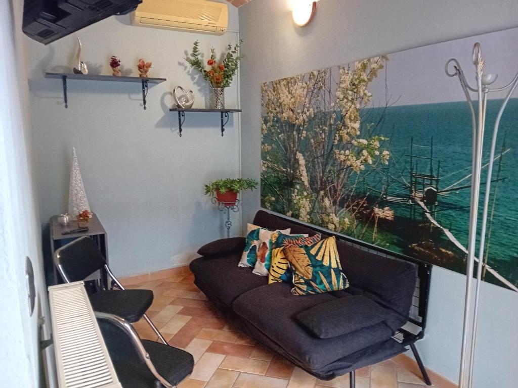 uma sala de estar com um sofá e uma pintura na parede em A due passi dal castello em Catignano