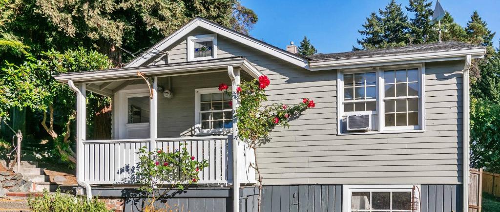 a small house with a porch and flowers on it at Charming Beach Cottage with Ocean Views & Sauna in Shoreline