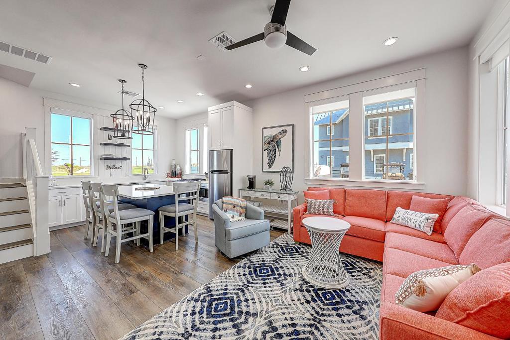 een woonkamer met een rode bank en een keuken bij Port Aransas Sunset in Mustang Beach