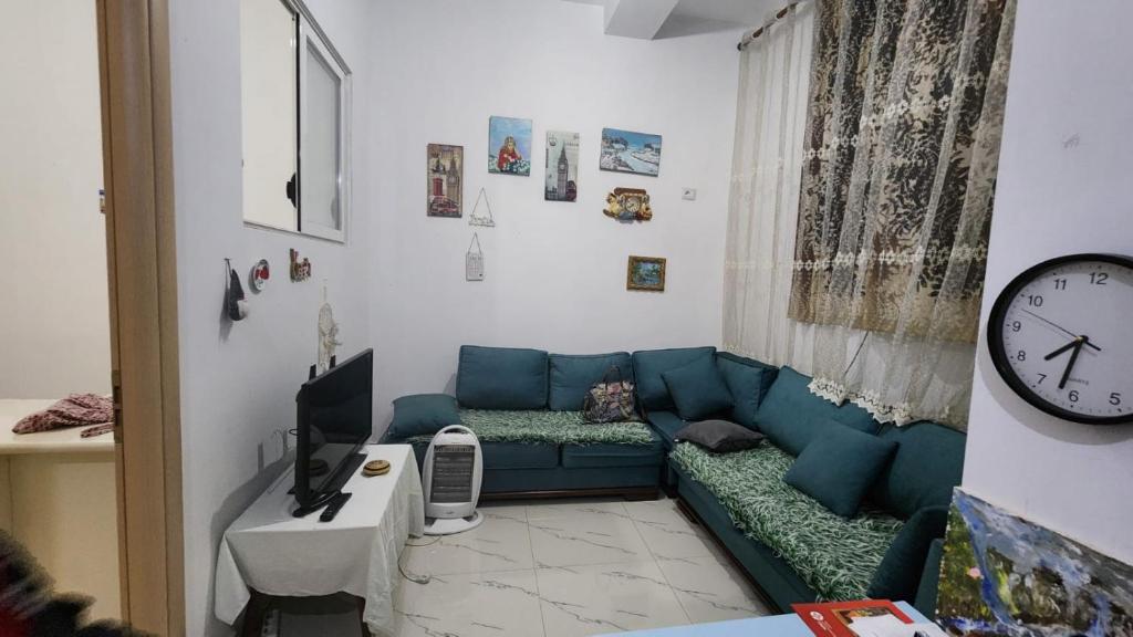 ein Wohnzimmer mit einem blauen Sofa und einer Uhr in der Unterkunft Lisi apartment in Tirane