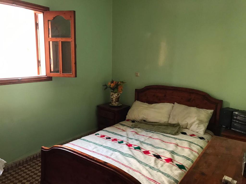a green bedroom with a bed with a wooden headboard at LoveWave House in Agadir