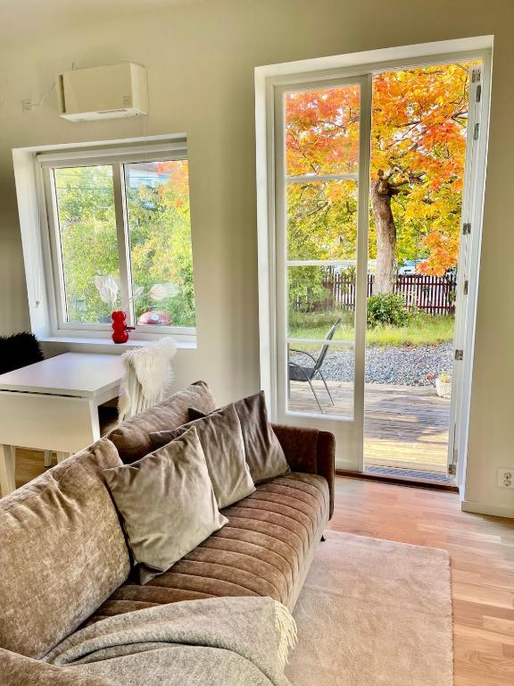 a living room with a couch and a sliding glass door at Röda Stugan in Örby, Älvsjö in Stockholm