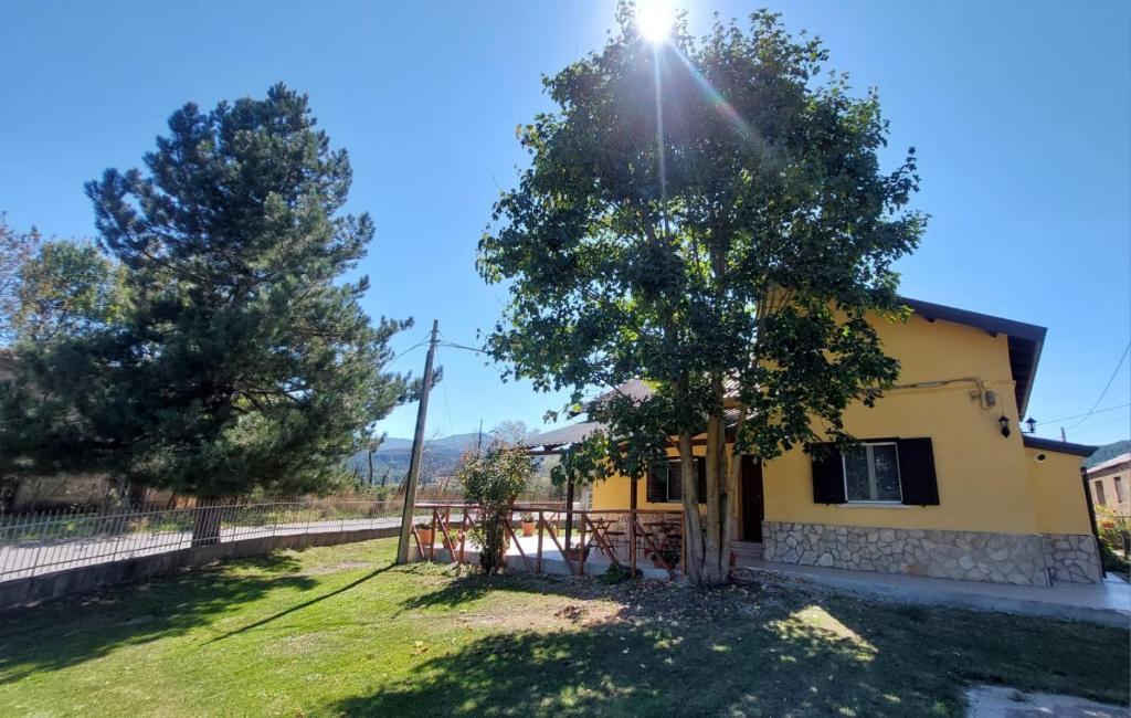 ein gelbes Haus mit einem Baum und einem Zaun in der Unterkunft Guzzolini Camere & Relax in Camigliatello Silano