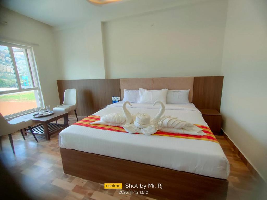 Un dormitorio con una cama con dos toallas blancas encima. en R2B Grand Hotel, en Kolār