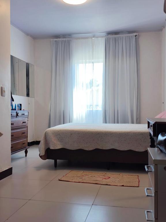 une chambre avec un lit, une commode et une fenêtre dans l'établissement Suíte Ampla Ideal para Família, à Garopaba