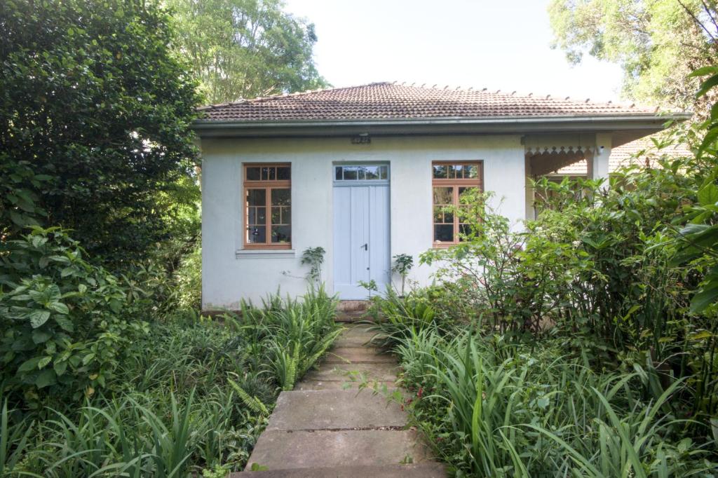 een klein wit huis met een witte deur bij Villa Sonnengarten Casa de Campo e Jardins in Venâncio Aires