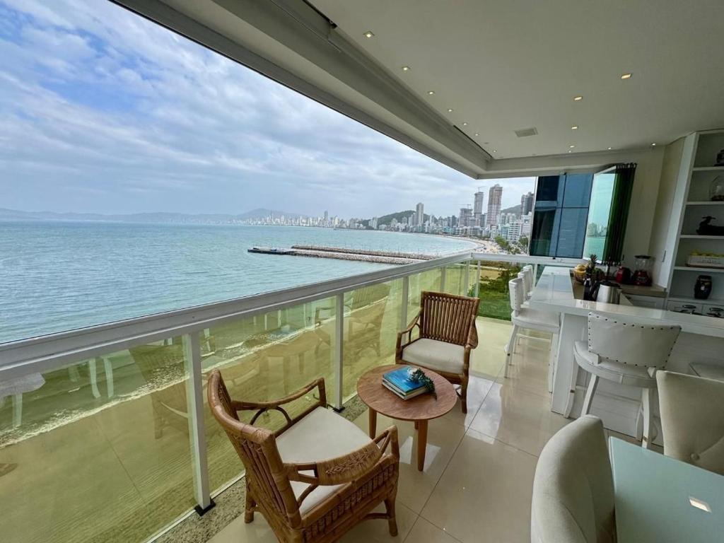un balcon avec des chaises et une vue sur l'océan dans l'établissement Apto Frente Mar Itapema Canto da Praia, à Itapema