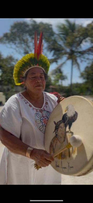 a woman wearing a headdress holding a plate with a picture on it at Aldeia Gaia Nordeste in Nísia Floresta