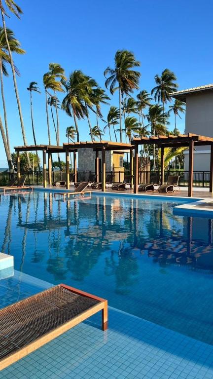 a large swimming pool with palm trees in the background at Seu Descanso a Beira Mar in Ilhéus