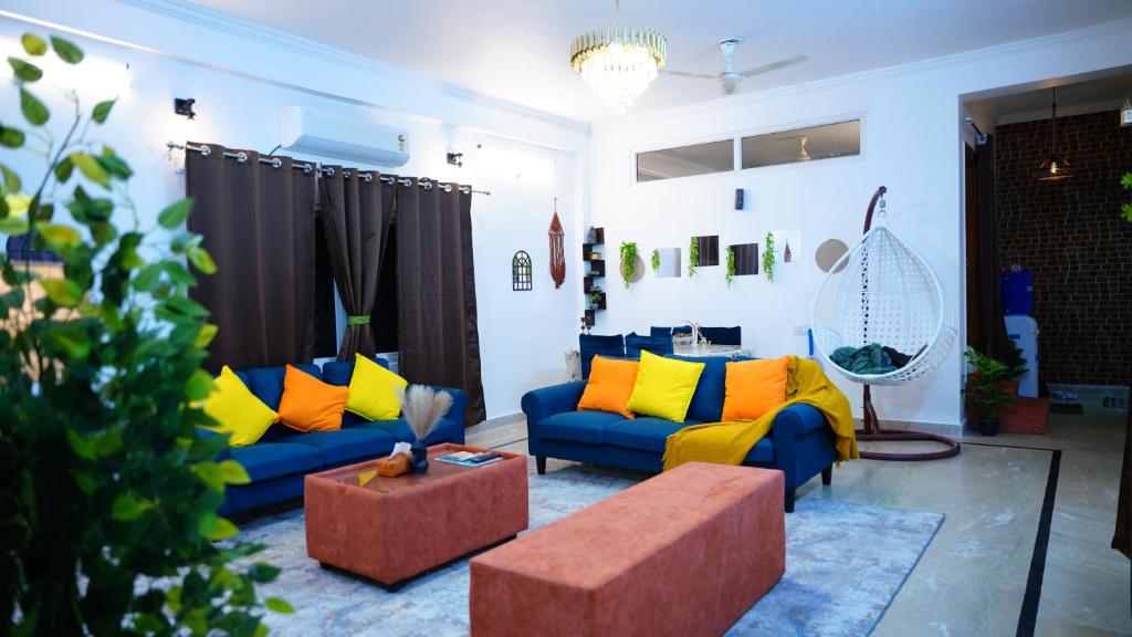 a living room with blue couches and yellow pillows at Emaar Homestays in Hyderabad