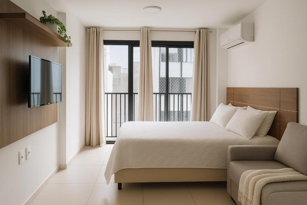 a bedroom with a bed and a tv and a couch at Studio com piscina Centro Rio de Janeiro in Rio de Janeiro
