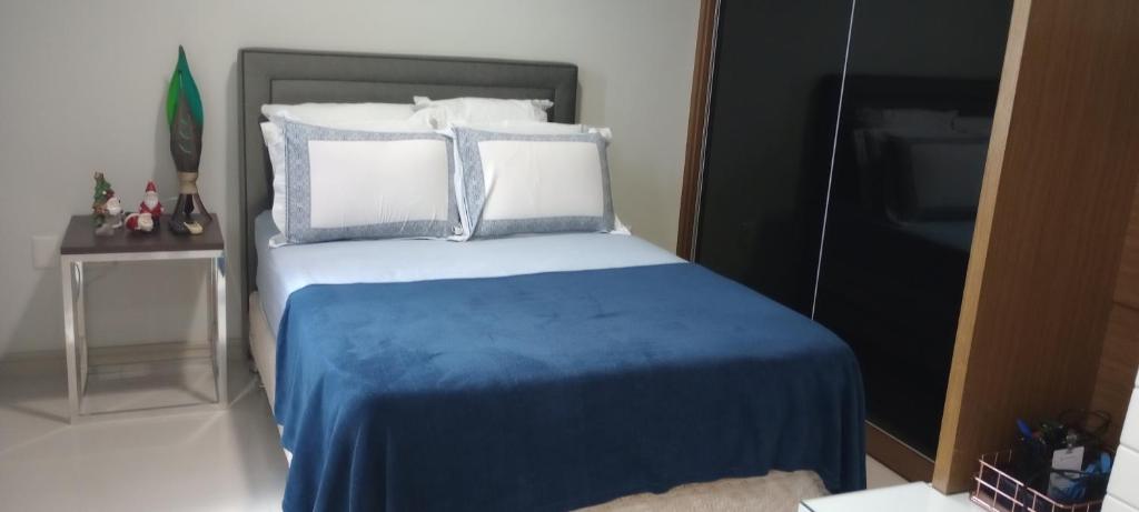 Un dormitorio con una cama con sábanas y almohadas azules. en Pousada Lima, en Volta Redonda