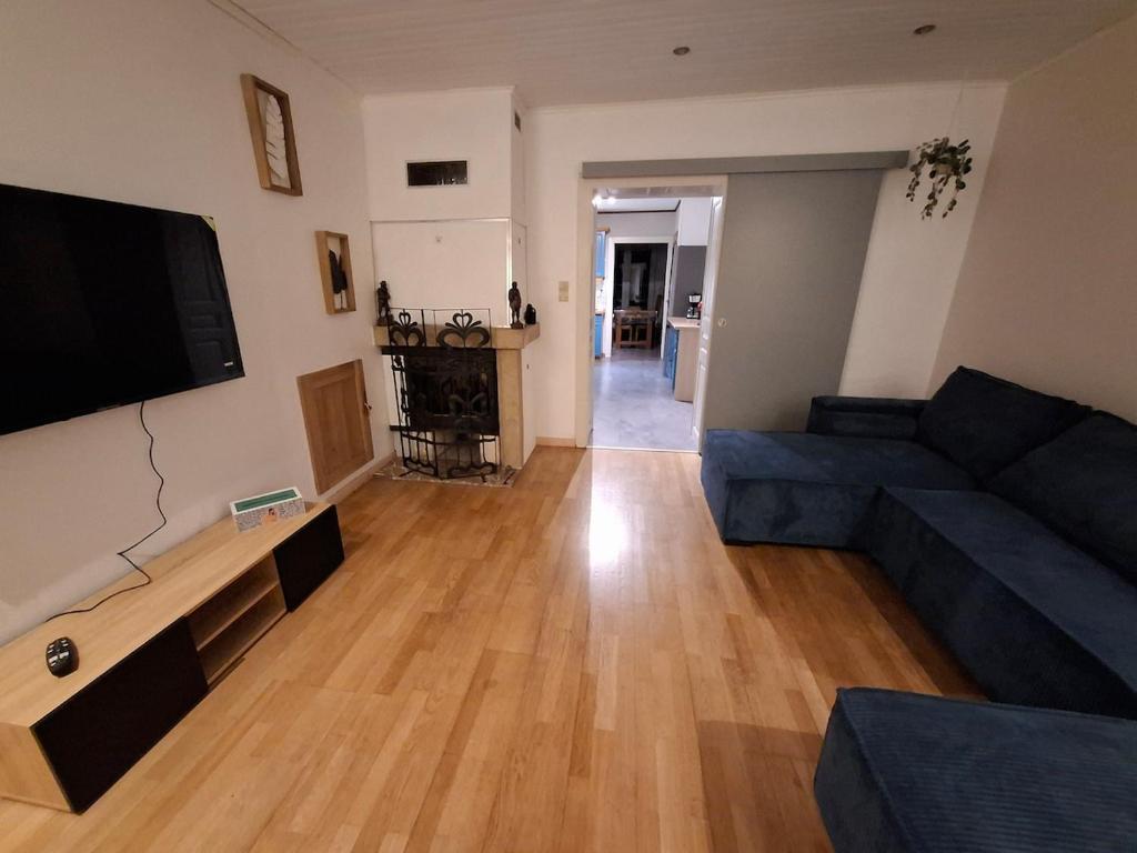 un salon avec un canapé bleu et une télévision à écran plat dans l'établissement Maison familiale en lisière de forêt, à Val-et-Châtillon