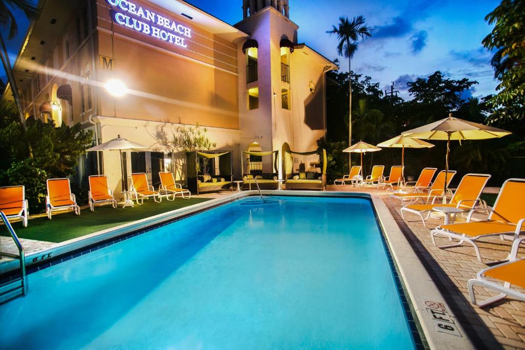 a pool in front of a hotel with chairs and umbrellas at Ocean Beach Club in Fort Lauderdale