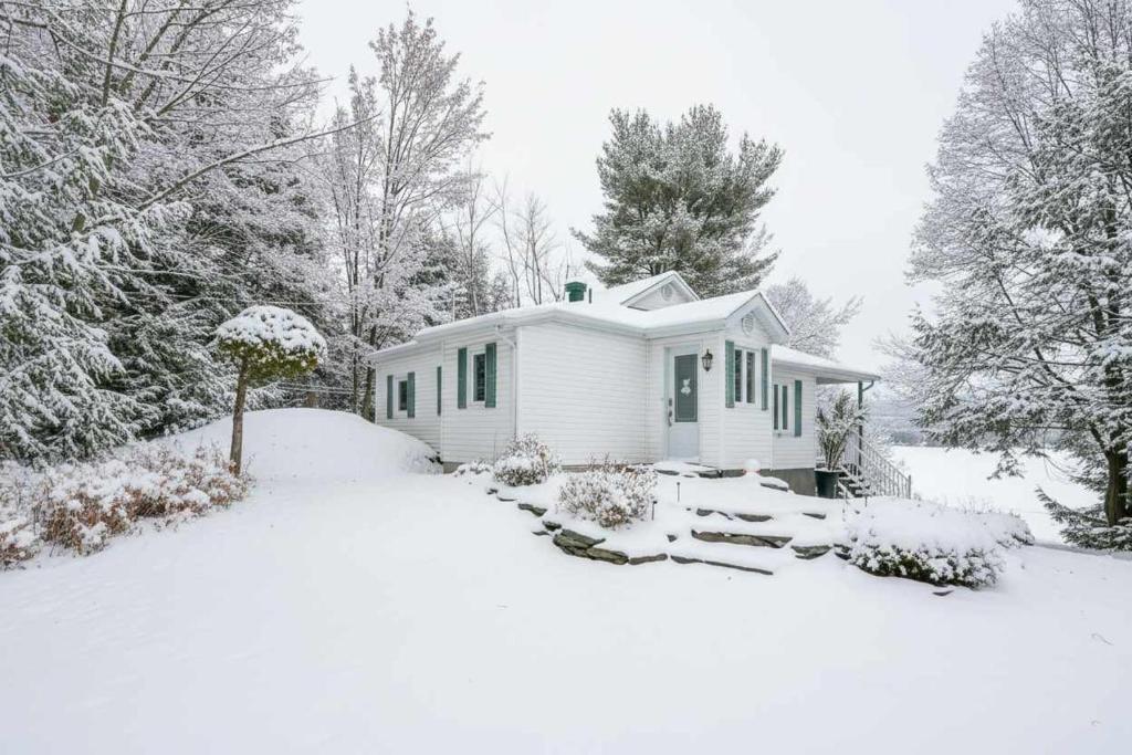 uma pequena casa branca com neve no chão em La Tranquilla - calm & comfort em Eastman