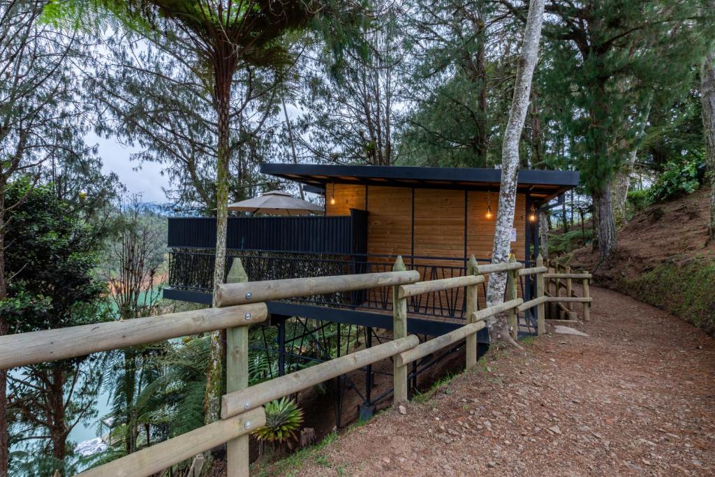 una cabaña en el bosque al lado de una valla en Unique, en Guatapé