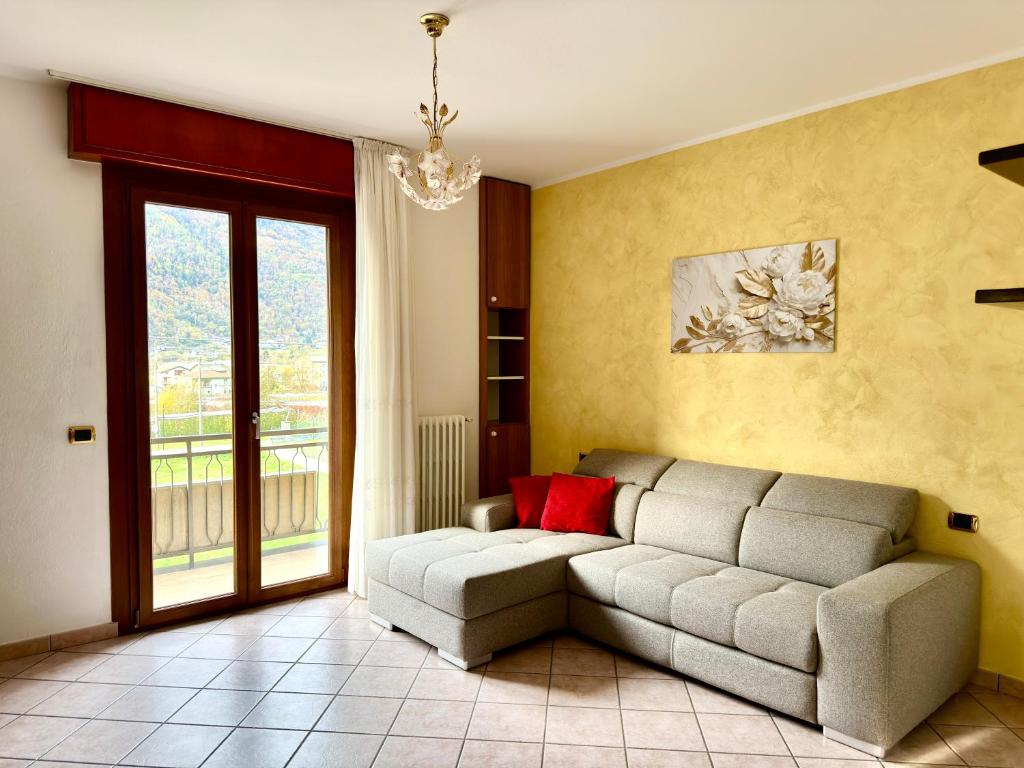 een woonkamer met een bank en een raam bij Ca' Prestin - Natura e Relax a 20 minuti da Bormio in Tovo di Sant'Agata