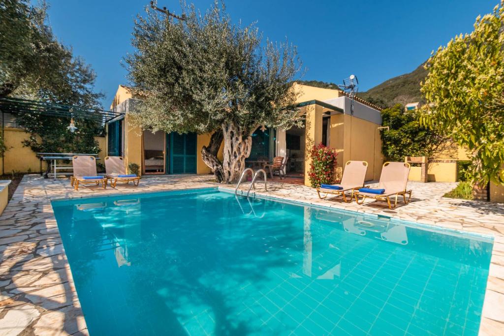 a swimming pool with chairs and a house at Barbati Beach - Villa Ithika in Barbati