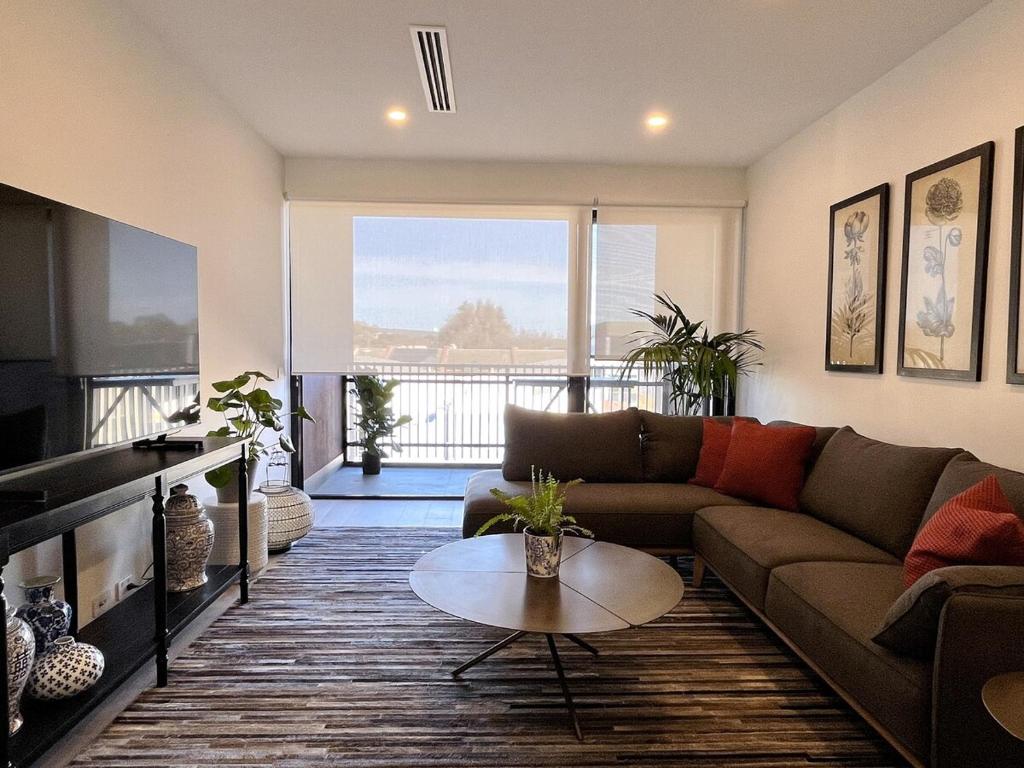 un soggiorno con un divano e un tavolo di Stylish CBD Retreat with 3BR,3BA,Balcony,2 Parking a Adelaide