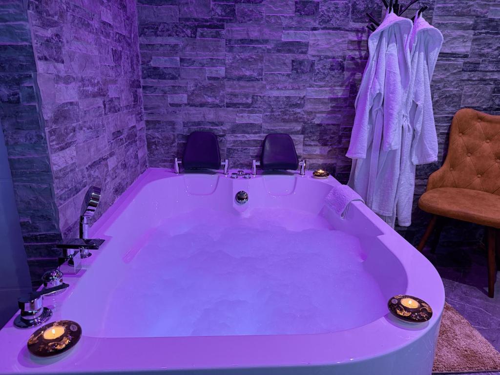 a purple bath tub with two chairs in a room at Dubai Spa Apartments in Novi Sad