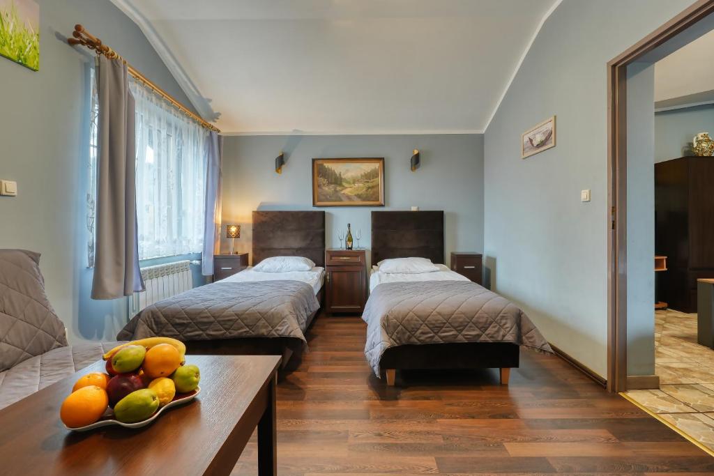 a room with two beds and a bowl of fruit on a table at Zajazd Karłów Restauracja & Pokoje Gościnne in Karłów