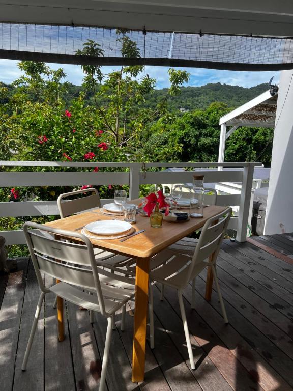a wooden table and chairs on a deck at Grand studio Plaisance et Fleurs in Le Vauclin