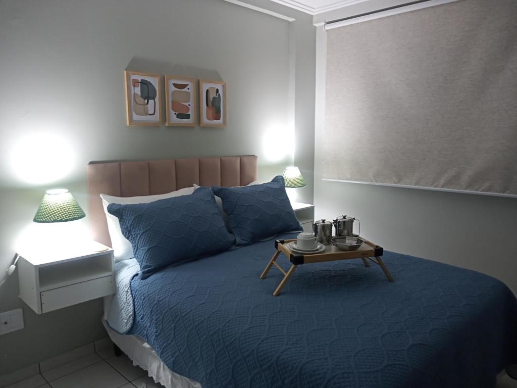 une chambre avec un lit bleu et une table dessus dans l'établissement Apê Aconchego Calhau - Próximo à Praia Litorânea, à São Luís