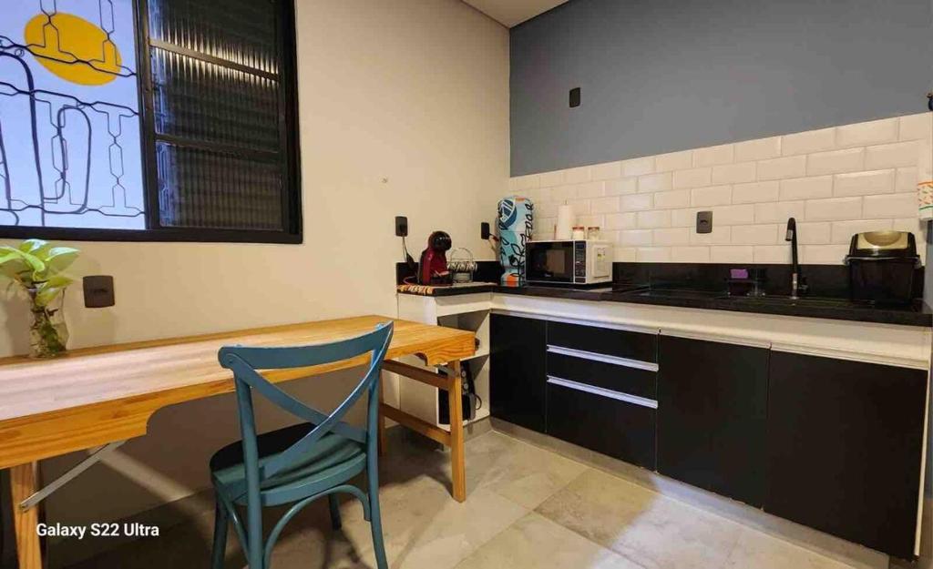 une cuisine avec une table en bois et une chaise bleue dans l'établissement Studio Astral, à Uberlândia