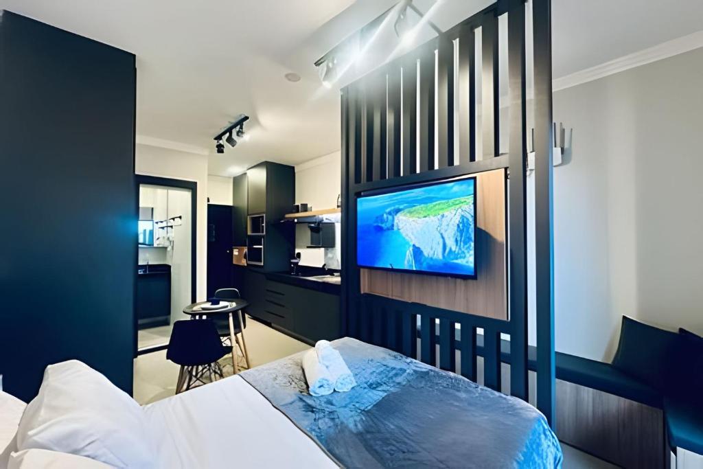 ein Schlafzimmer mit einem Bett und einem Fernseher an der Wand in der Unterkunft Loft 306 - Praticidade e estilo na esquina da Ufu in Uberlândia