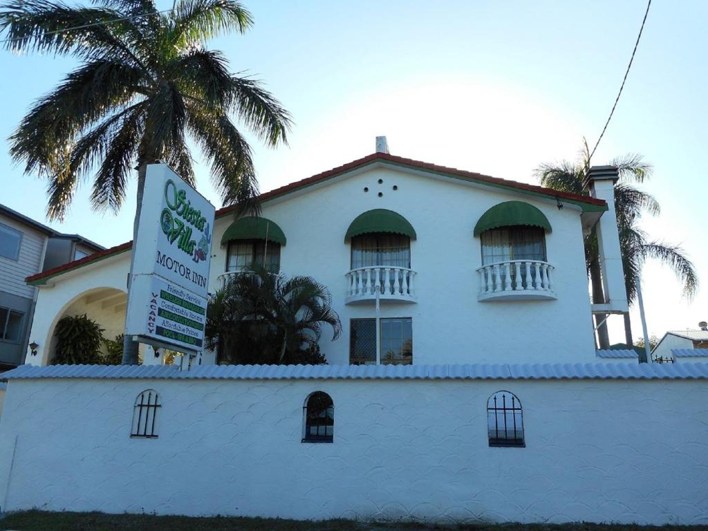a white building with a palm tree in front of it at Glenlyon Lodge - Gladstone in Gladstone