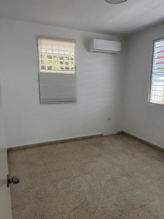 StayDelRom Cozy 3BR Home 9 Min to Airport 5 to Mall of San Juan 2 to Restaurants في سان خوان: غرفه فاضيه فيها شباك ومروحه
