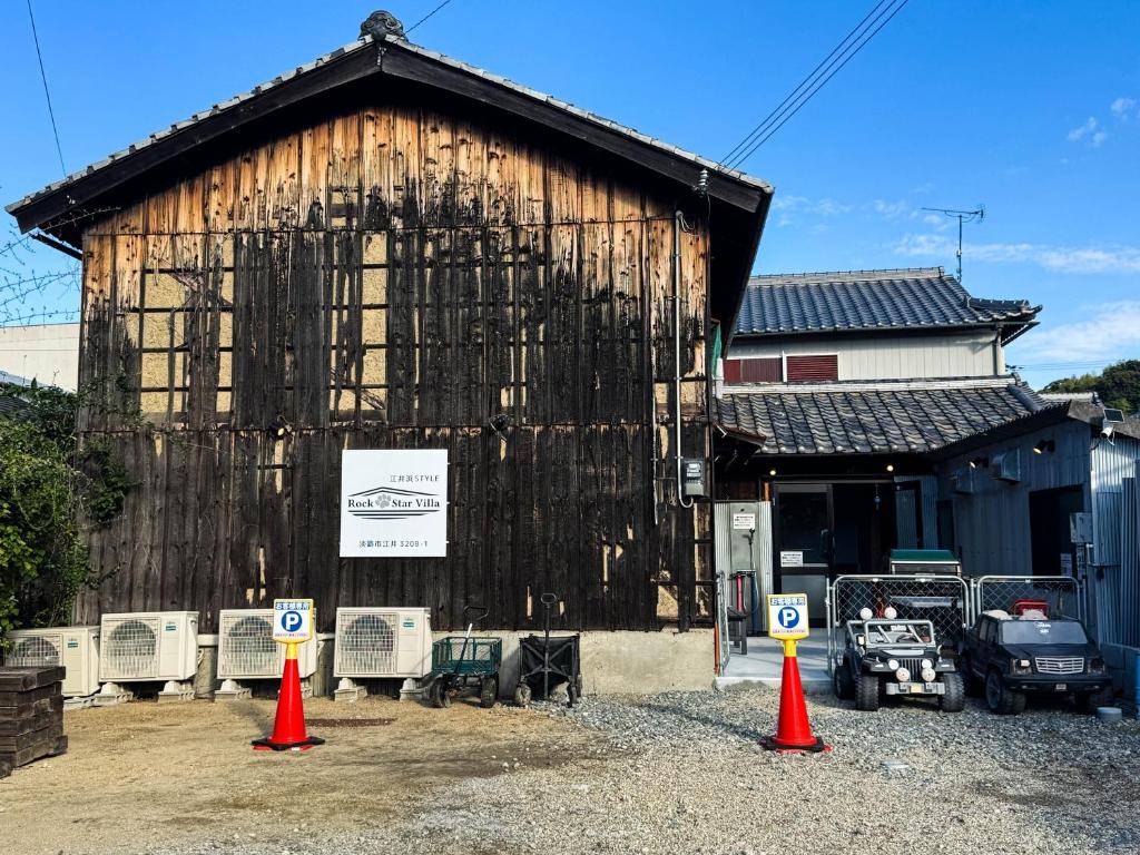 ein großes Holzgebäude mit orangefarbenen Kegeln davor in der Unterkunft Rockstar Villa 江井浜STYLE in Awaji
