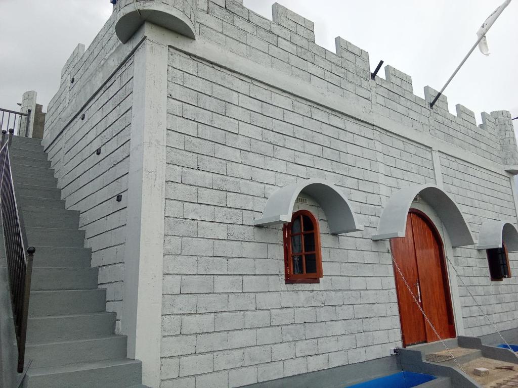 Un edificio de ladrillo blanco con una puerta y escaleras rojas. en Castello, en Tomohon