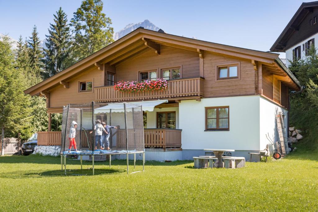 two people standing on a swing in front of a house at Active Chalet in Maria Alm am Steinernen Meer