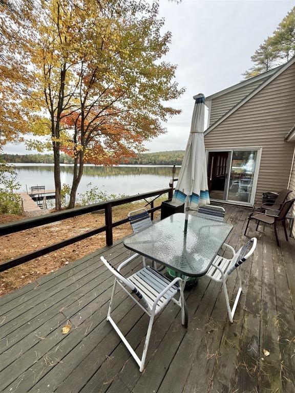 a table and chairs on a deck with an umbrella at BARKER POND ESCAPE LIMIT 8 villa in Hiram