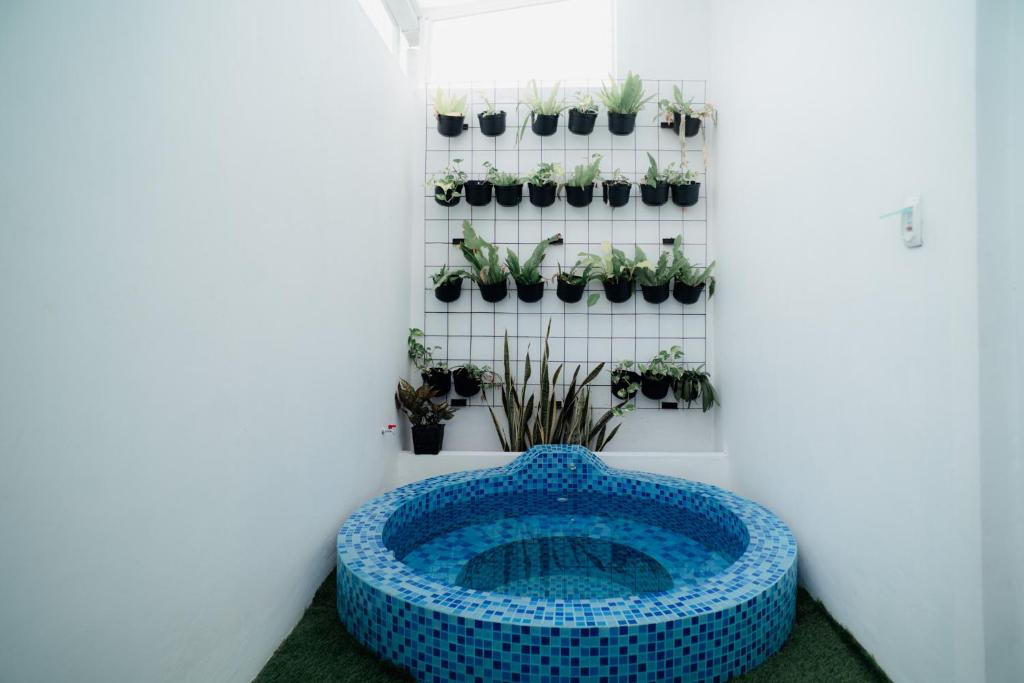 een blauw bad in een kamer met potplanten bij Been View Homestay in Adi Sutjipto