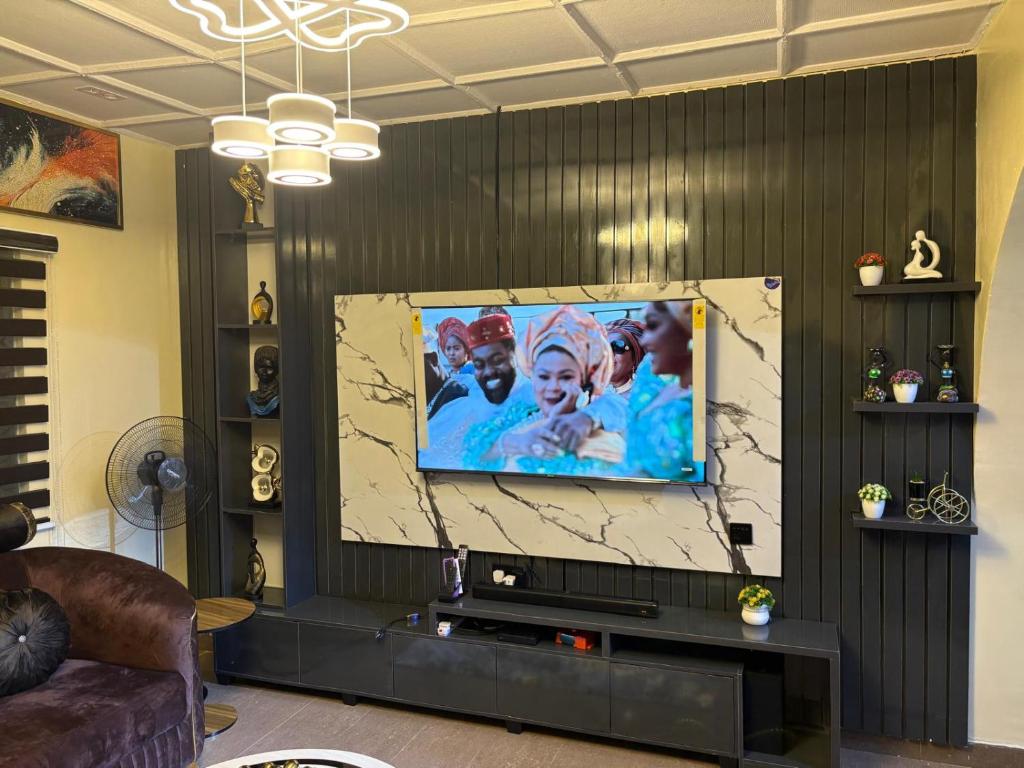 uma sala de estar com uma televisão de ecrã grande numa parede em Avapartmentrentals em Okunola