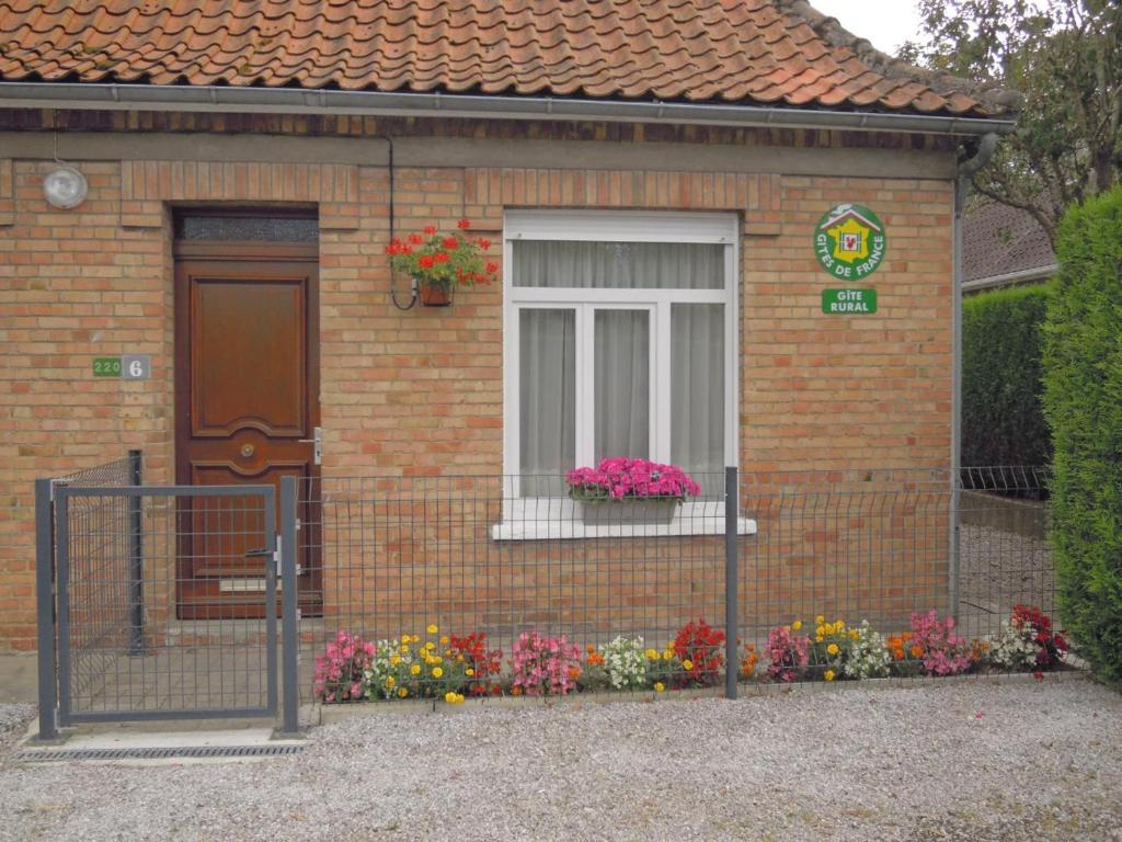 une petite maison avec des fleurs devant une fenêtre dans l'établissement Charmante Maison à Recques-sur-Hem, 2 pers, Animaux Acceptés, Jardin, Proche Calais et St Omer - FR-1-376-58, à Recques-sur-Hem