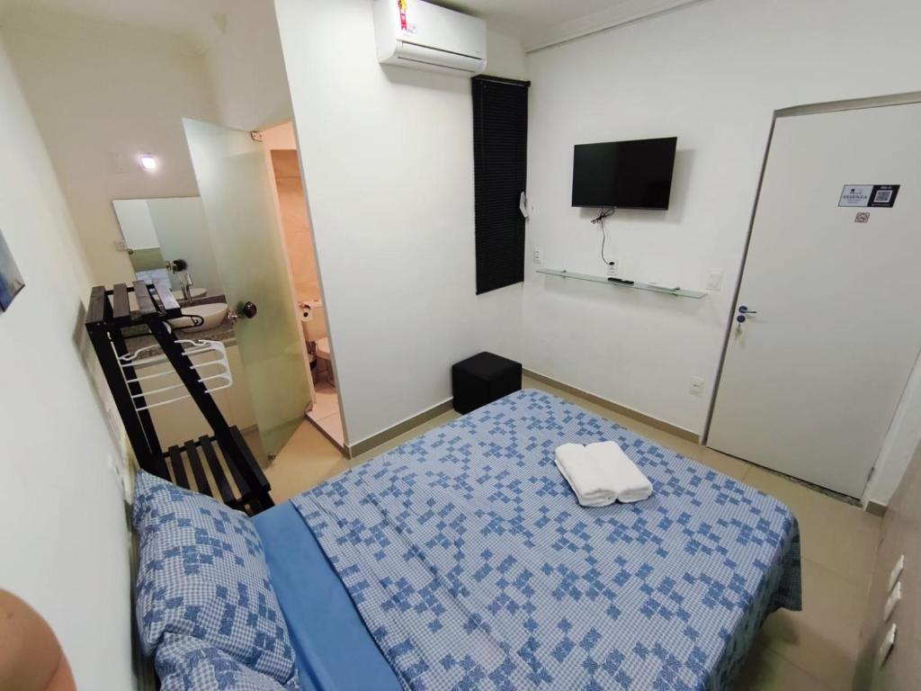 Una pequeña habitación con una cama y un televisor. en Essenza Suites Natal, en Natal