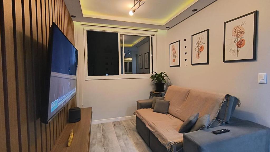 a living room with a couch and a flat screen tv at Belíssimo apartamento in Sao Paulo