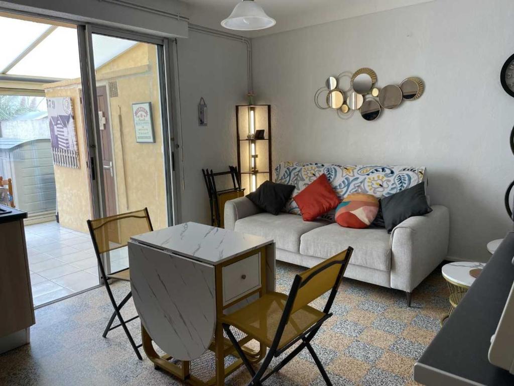 ein Wohnzimmer mit einer Couch und einem Tisch und Stühlen in der Unterkunft Maisonette plain-pied avec cour fermée, proche plage et commerces - FR-1-476-248 in La Faute-sur-Mer