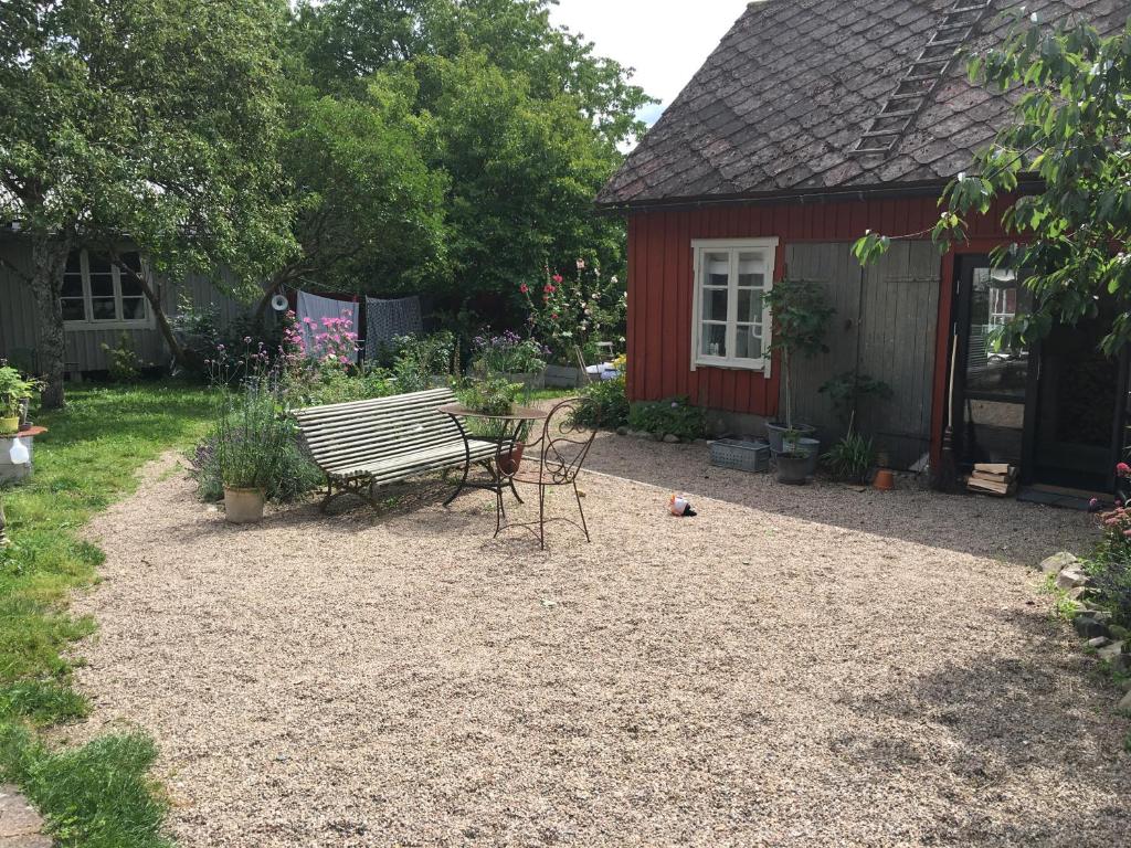 um banco num quintal ao lado de um barracão vermelho em Harrys Hardware Home em Brösarp