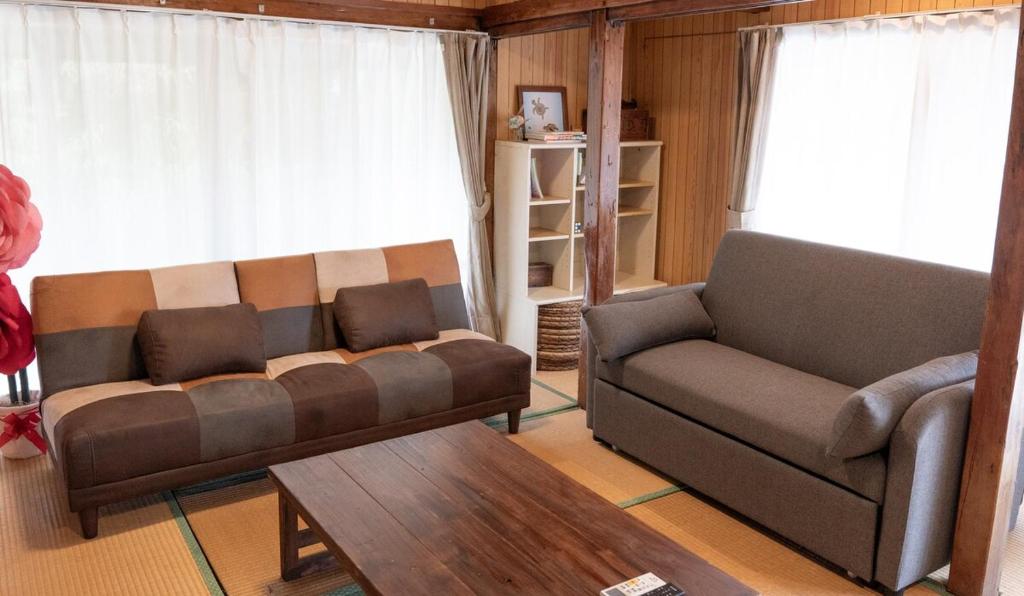a living room with a couch and a coffee table at 羽地古民家 かめたろうやー in Nakaoshi