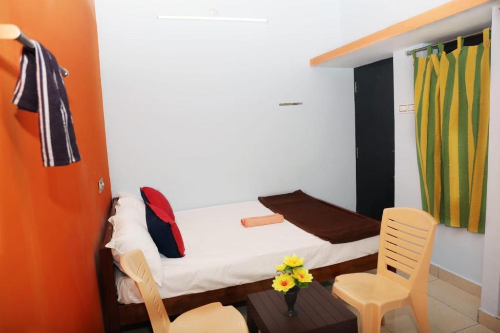 ein kleines Schlafzimmer mit einem Bett und einem Stuhl in der Unterkunft Balaji home stay in Puducherry