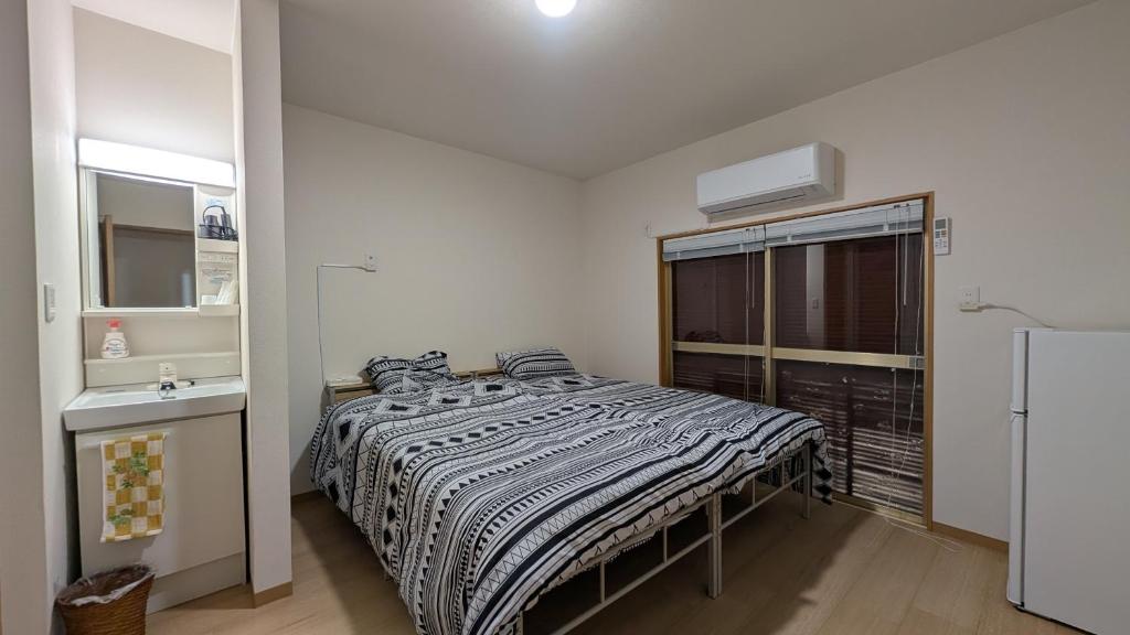 1 dormitorio con 1 cama y lavamanos. en Ippaku 一泊, en Izumisano