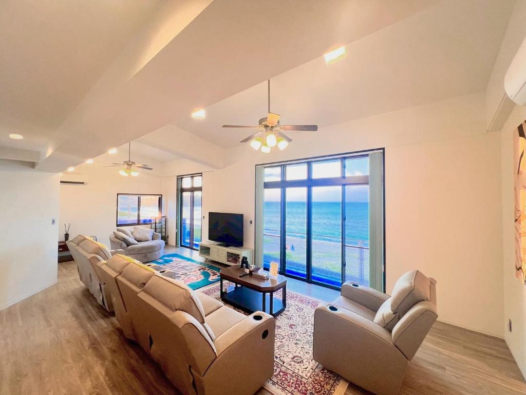 a living room with couches and a television and the ocean at SEA BASE Onna in Onna