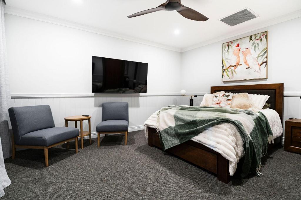 a bedroom with a bed and two chairs and a tv at Rileysview in Kilcoy
